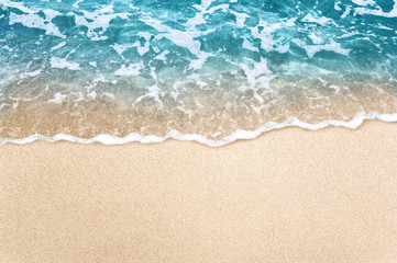Soft blue ocean wave on clean sandy beach background