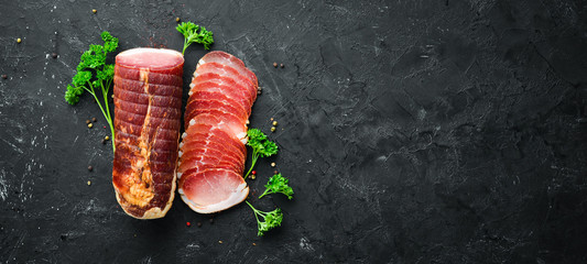 Smoked meat with spices and herbs. On a black wooden background. Top view. Free space for your text.