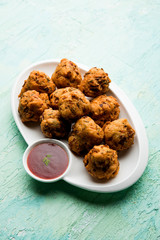rava Bhajj or bhajiya also known as suji Pakoda or semolina Pakora, served with tomato ketchup. selective focus