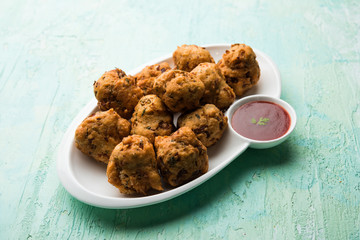 rava Bhajj or bhajiya also known as suji Pakoda or semolina Pakora, served with tomato ketchup. selective focus