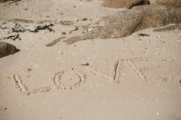 closeup of love word writting in the sand on the beach