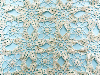 Hand knitted traditional lace mat doily isolated on light blue background.