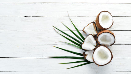 Fresh coconut on a white wooden background. Tropical Fruits. Nut. Top view. Free space for your text.