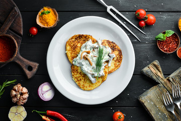 Potato pancakes with mushroom sauce. On a wooden background. Top view. Free space for your text.