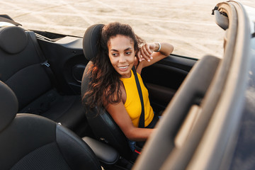 Optimistic young pretty woman driving the car at the beach