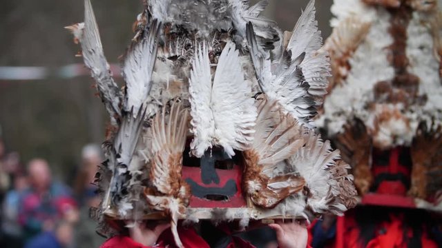 Red mask with black mustache, Vendetta alike but bulgarian kuker edition, decorated with chicken feathers