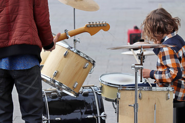 Street musicians play guitar and drums on a sidewalk. Concert in a city, urban performers outdoor