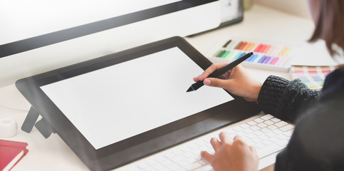 Young female graphic designer working with blank tablet in creative workplace