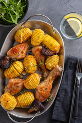 Barbecued chicken leg with boiled potatoes and vegetables on black background. Copy space. Top view.
