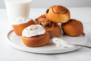 Delicious Cinnamon Rolls with cheese cream on a white plate. Copy space.