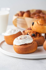 Delicious Cinnamon Rolls with cheese cream on a white plate. Copy space.