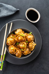 Asian dumplings in bowl, chopsticks, plates. Asian table setting. Chinese dumplings for dinner. Selective focus. Asian style decoration. Chinese fresh homemade food. Closeup