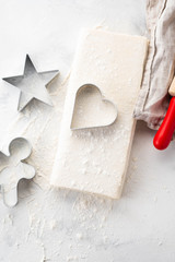 Raw puff pastry dough lies on a white table. Figures for baking cut metal mold. Copy space, top view.