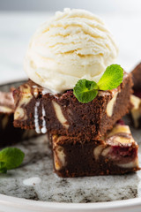 Chocolate brownie with vanilla ice cream, rasberry and mint on a white background. Copy space.