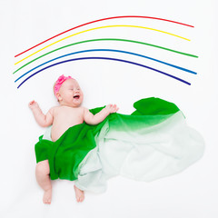 top view of cute infant laughing baby wrapped in a green scarf depicting a cloud under the painted rainbow