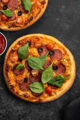 Freshly baked homemade pizza on a black background. View from above.