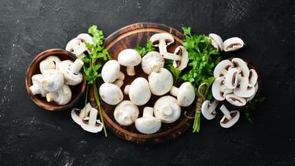 Champignons mushrooms on a black wooden table. Top view. Free space for text.