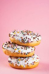 Donuts with icing on pastel pink background. Sweet donuts. Copy space.