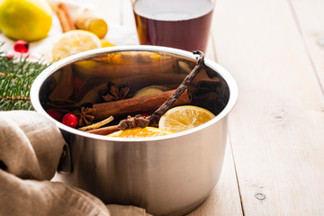 Mulled wine hot drink with citrus, apple and spices in aluminum casserole and Fir branch on background.