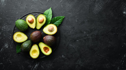 Fresh avocado with leaves on a black background. Top view. Free space for your text.