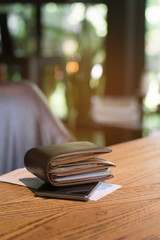 Soft tone of Money and credit card in a leather wallet on wooden table and bill slip background