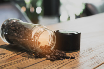 Roasted coffee beans on wooden table in cafe with sunshine background.