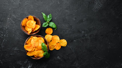 Potato chips with spices on a black background. Snacks to beer. Top view. Free space for text.