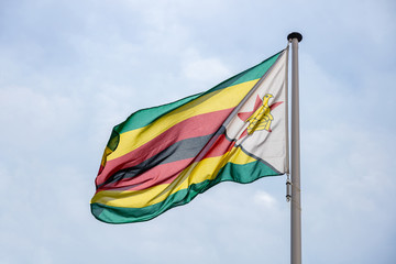Zimbabwe flag waving against clear blue sky