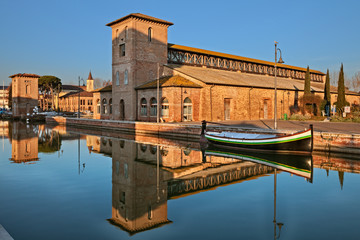 Cervia, Ravenna, Emilia-Romagna, Italy: the port canal with the ancient salt warehouse - obrazy, fototapety, plakaty