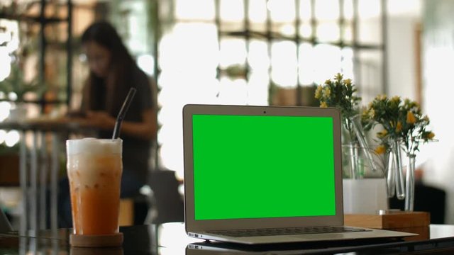 A laptop computer with a key green screen set on coffee shop.