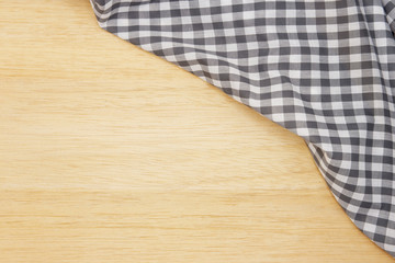 Wrinkled grey gingham fabric on rustic light brown wood background, with copy space. 