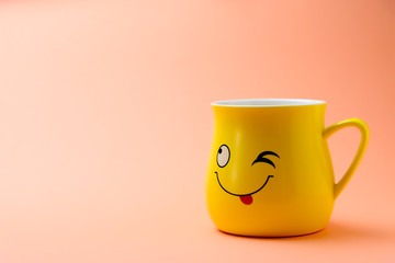 Yellow cup with a winking smile on a colored background