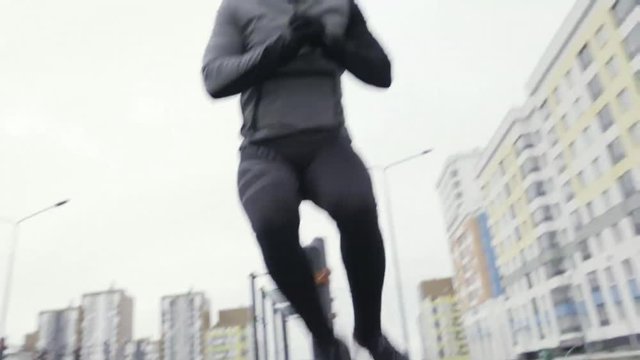 Close up for the legs of sportsman in black tracksuit jumping to the left and to the right at sports area. Action. A muscular man having athletic training, healthy lifestyle concept.