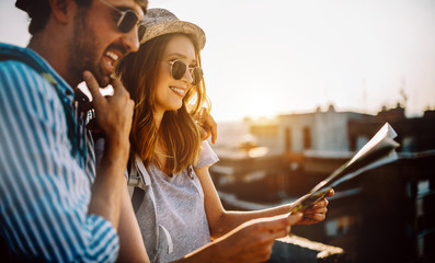 Happy young couple of travellers holding map in hands