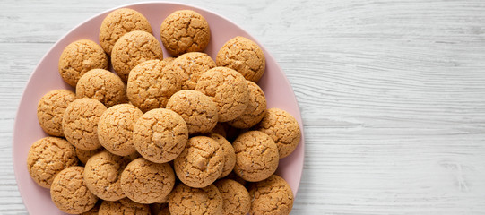 Almond cookies on a pink plate over white wooden background, top view. Flat lay, overhead, from above. Copy space.