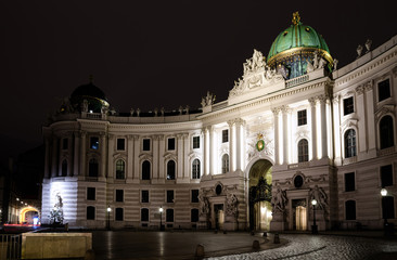 Fototapeta na wymiar The Hofburg Palace in Vienna, ancient baroque imperial palace. Entrance of the Saint Michael wing in Michaelerplatz square at night