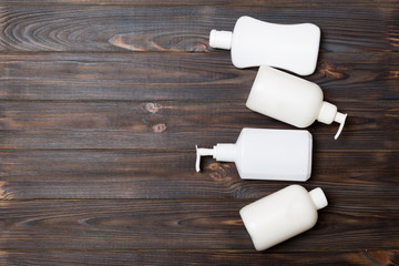 Set of White Cosmetic containers on wooden background, top view with copy space. Group of plastic bodycare bottle containers with empty space for you design