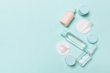 Group of small bottles for travelling on blue background. Copy space for your ideas. Flat lay composition of cosmetic products. Top view of cream containers with cotton pads