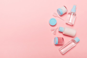 Top view composition of small travelling bottles and jars for cosmetic products on pink background. Facial skin care concept with copy space for your design