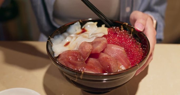 Woman having shashimi don in japanese restaurant