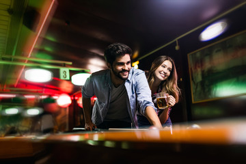 Happy young man playing snooker with his girlfriend. Happy loving couple.