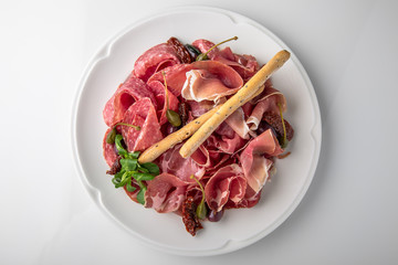 Slicing gourmet meat, prosciutto from beef and pork with berries, cheese, vegetables. Banquet festive dishes. Gourmet restaurant menu. White background.