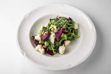 Nutritious, healthy, vitamin, dietary salad of boiled beets, cheese, arugula and nuts. Banquet festive dishes. Gourmet restaurant menu. White background.
