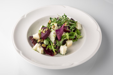 Nutritious, healthy, vitamin, dietary salad of boiled beets, cheese, arugula and nuts. Banquet festive dishes. Gourmet restaurant menu. White background.