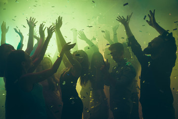 Close up photo of many party people dancing clubbing green lights confetti flying everywhere...