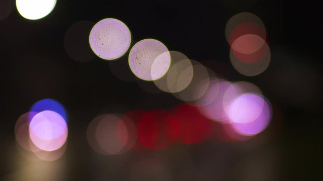 Blurred vehicle headlights and traffic lights on an urban boulevard.