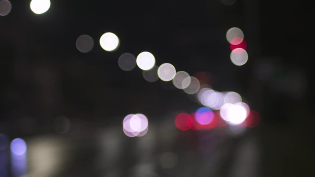 Blurred street lamps, vehicle headlights and traffic posts shot in the late evening on an urban boulevard.