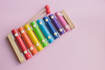 Rainbow Colored Wooden Toy Xylophone on pink bacground. toy glockenspiel made of metal and wood