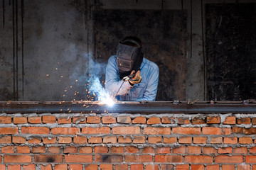 Industry worker welding iron pieces on new building