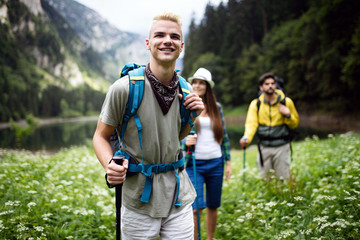 Group of smiling friends hiking with backpacks outdoors. Travel, tourism, hike and people concept.